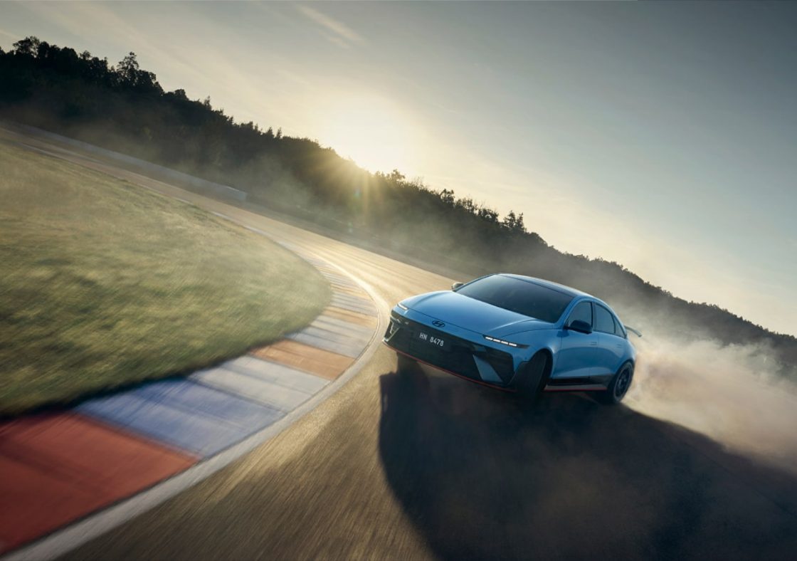 Voiture bleue en drift sur circuit au coucher du soleil.