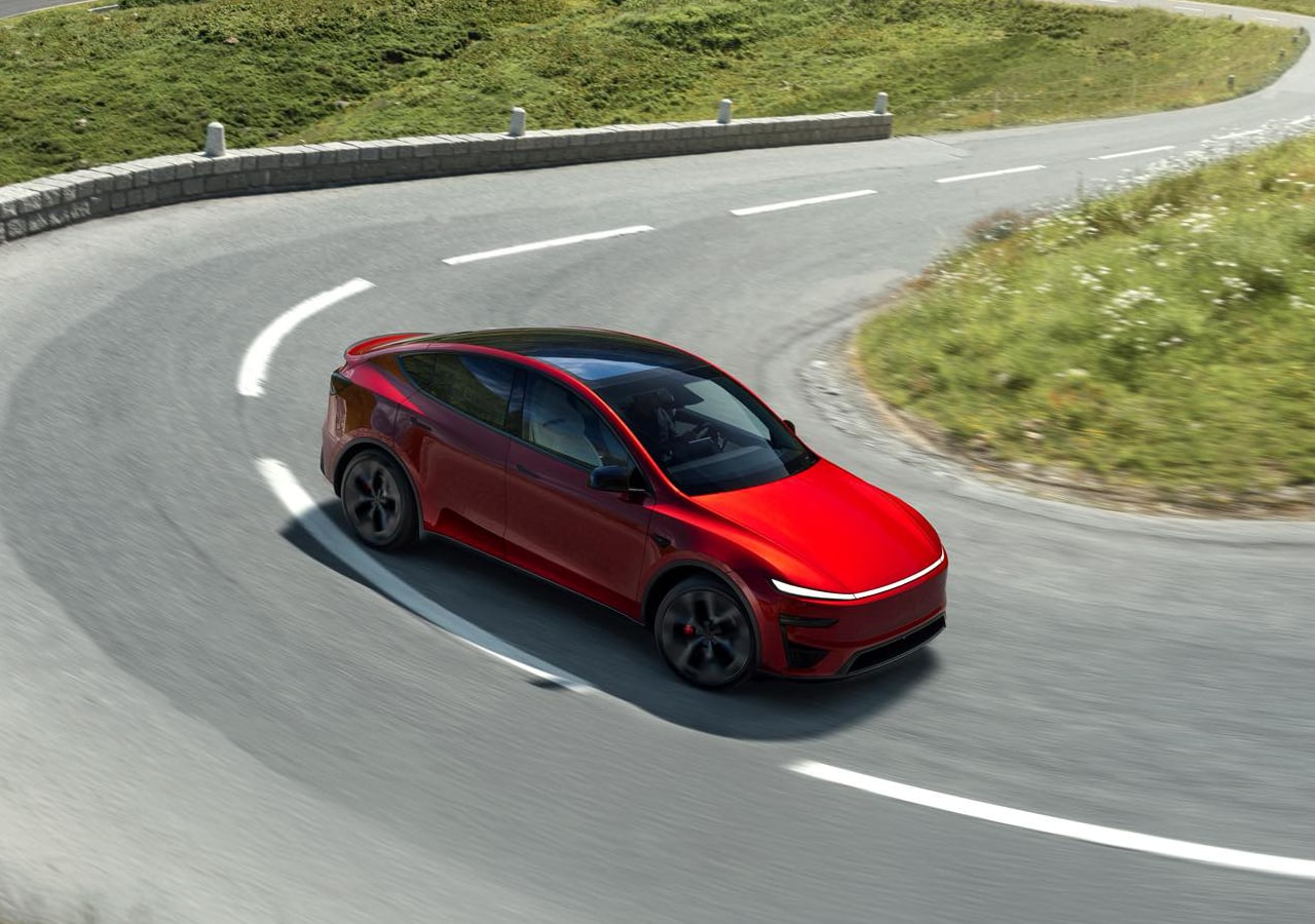 Voiture rouge sur route sinueuse montagneuse.